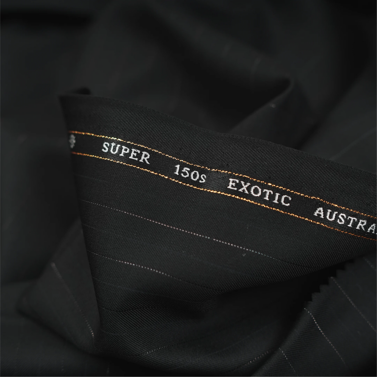 Close-up of OCM Aristo Merino Wool 150 black fabric with pinstripes and branded selvedge
