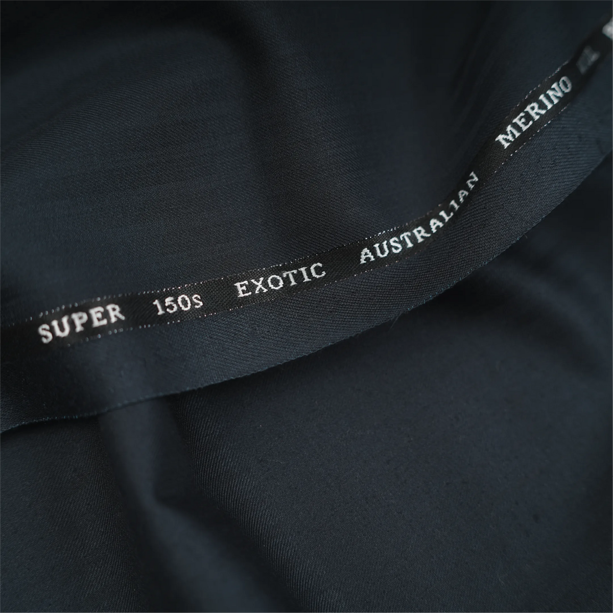 Close-up of OCM Aristo Merino Wool 150 dark navy blue fabric with branded selvedge