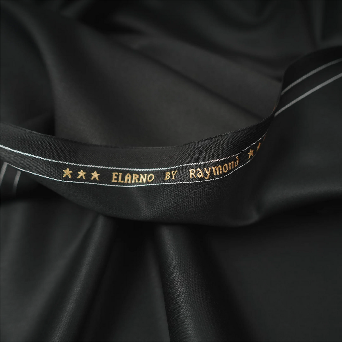 Close-up of Raymond Elarno black suiting fabric with branded selvedge