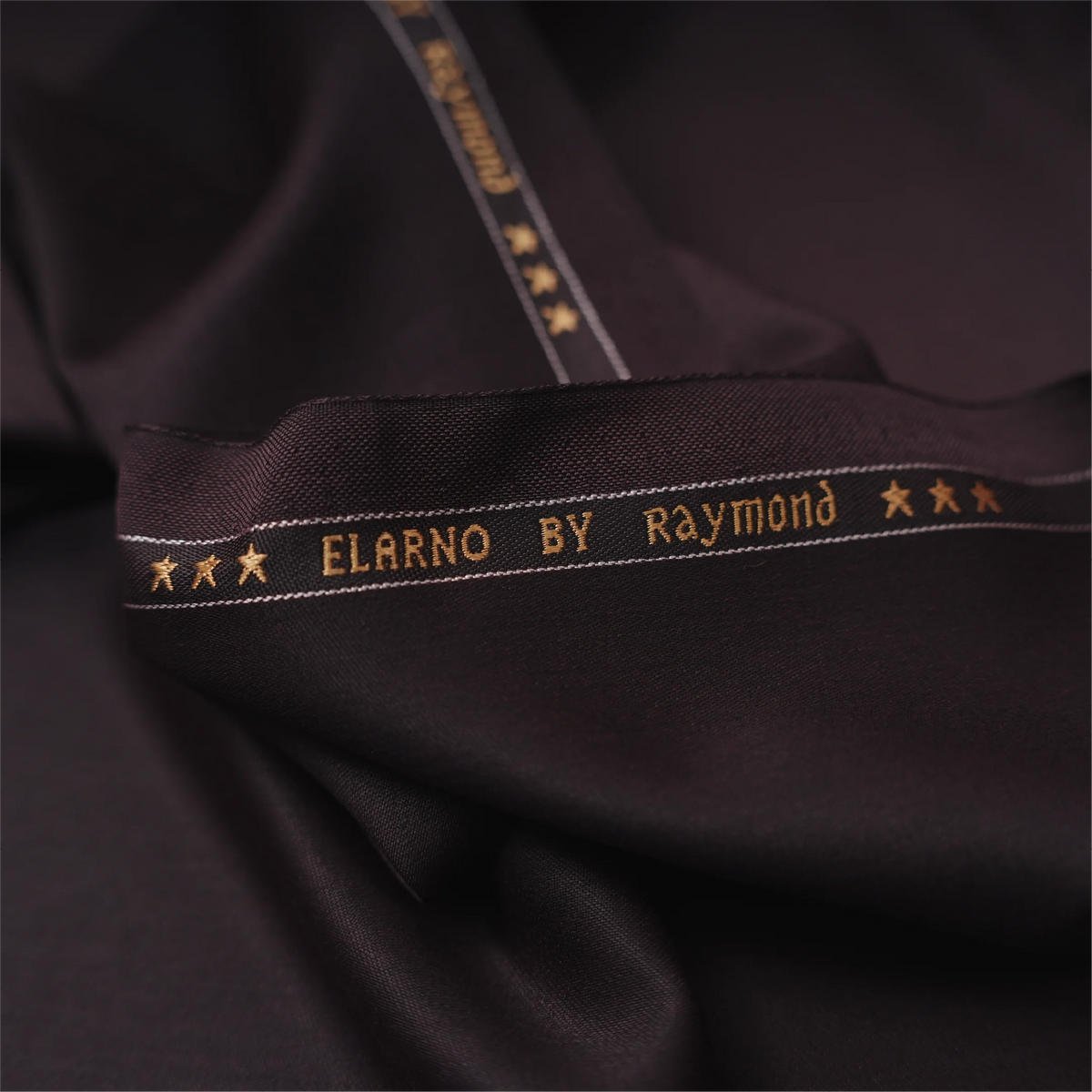 Close-up of Raymond Elarno dark wine suiting fabric with branded selvedge