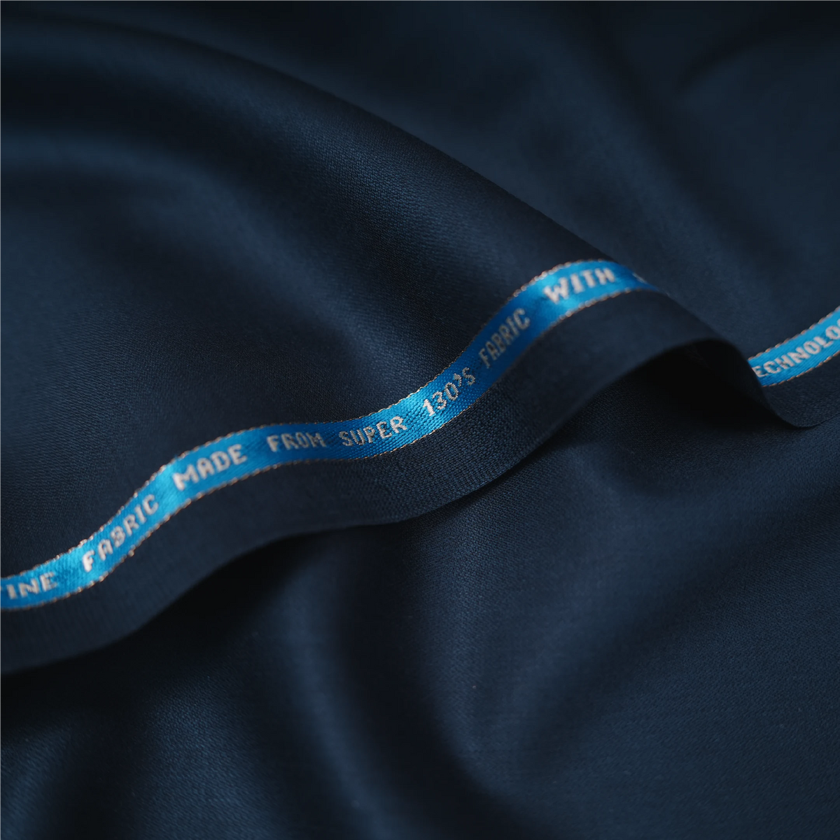 Close-up of Raymond Lexican Merino Wool 130 dark navy blue fabric with branded selvedge