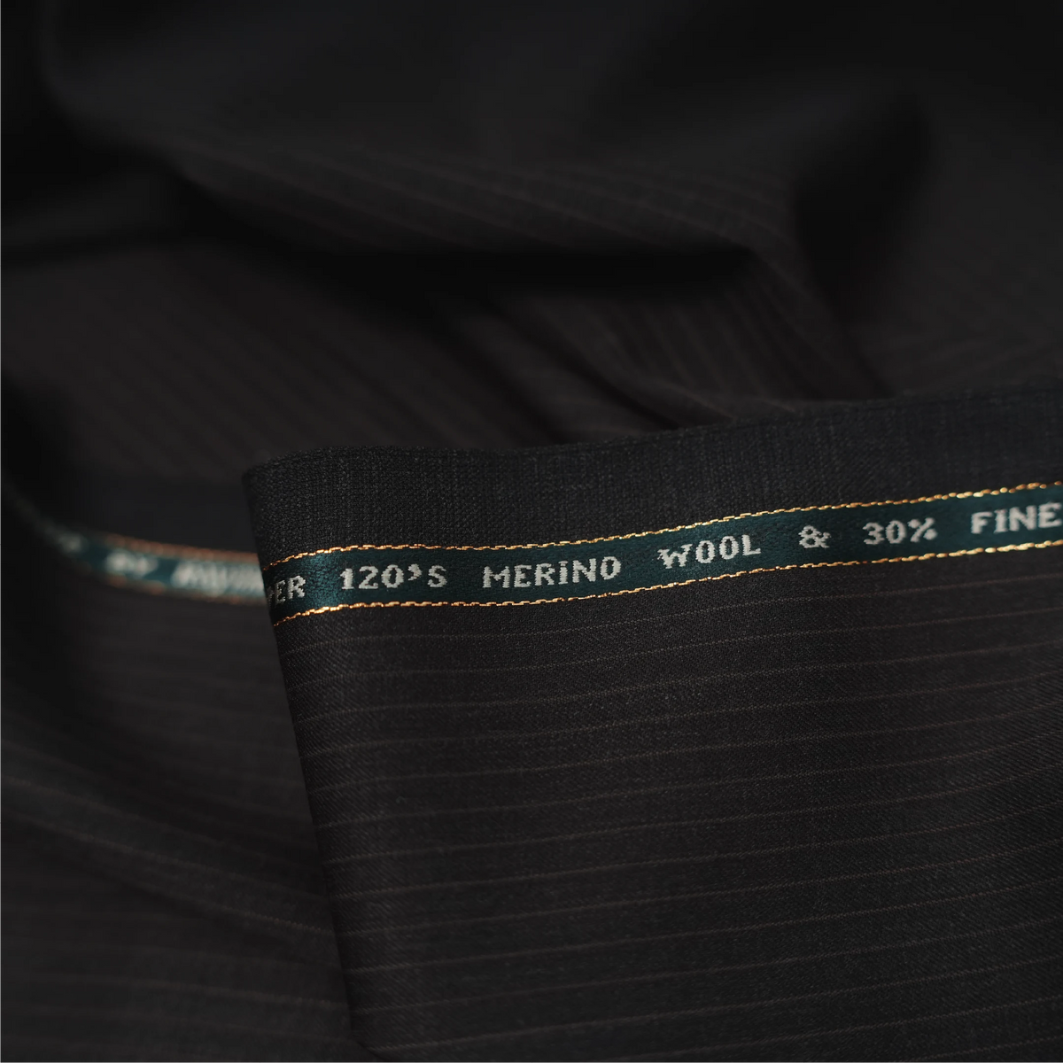 Close-up of Raymond Lexican Merino Wool 130 dark teal fabric with red checks and branded selvedge