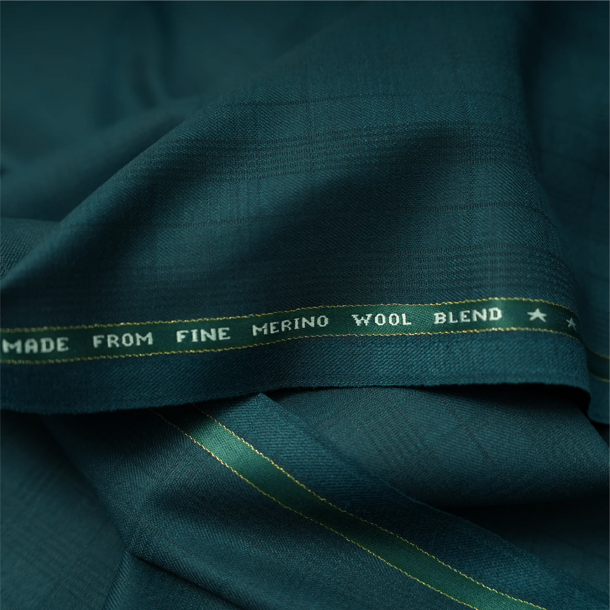 Close-up of Raymond Spanax Merino Wool Blend Stretch dark teal green fabric with branded selvedge