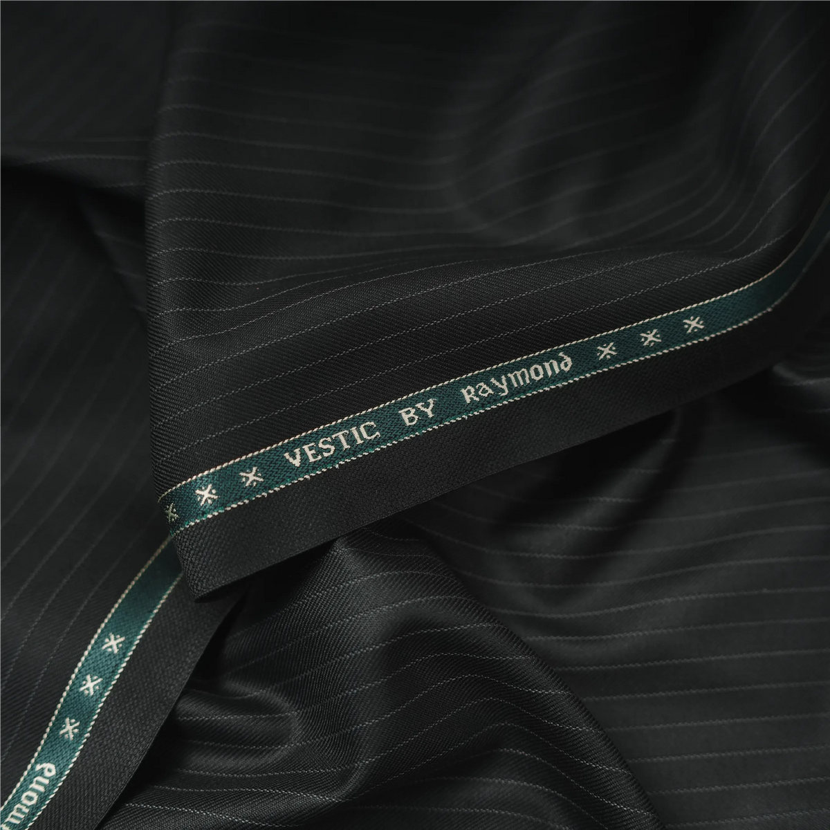 Close-up of Raymond Vestic black pinstripe suiting fabric with branded selvedge
